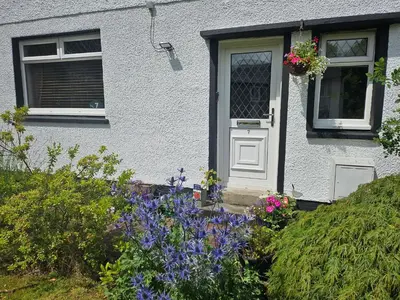 a house with flowers in front of a door at Spacious 2 bedroom house on the edge of Balloch in Balloch