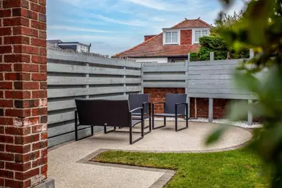 a patio with two chairs and a fence at Berelands House - Donnini Apartments in Prestwick