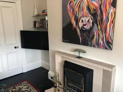 a painting of a dog hanging over a fireplace at Beautiful traditional top floor flat in the center of Largs in Largs