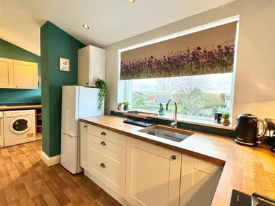 a kitchen with a sink and a large window at Chestnut Cottage in Dalmellington