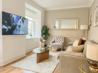 a living room with a couch and a tv on a wall at Cozy 1 bed Blythswood Apartment in Glasgow