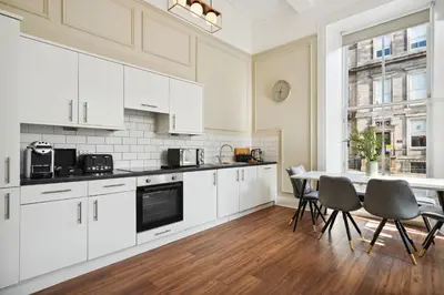 a kitchen with white cabinets and a table and chairs at (G1) Elegant 2 bed Blythswood Apartment in Glasgow