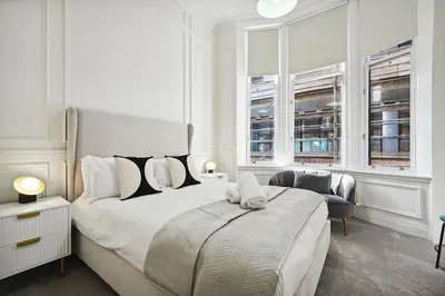 a white bedroom with a large bed and two windows at (G3) Grand 2 bed Blythswood Apartment in Glasgow