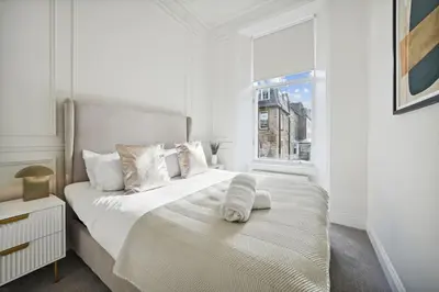 a white bedroom with a large bed with a window at (G3) Grand 2 bed Blythswood Apartment in Glasgow