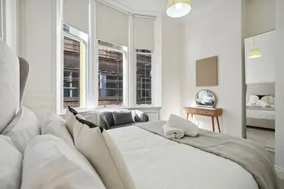 a white bedroom with a large bed and windows at (G3) Grand 2 bed Blythswood Apartment in Glasgow