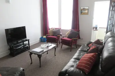 a living room with a leather couch and a tv at Cumbrae View House (Licence no NA00109F) in Largs