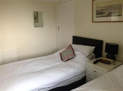 a bedroom with two white beds and a nightstand with a pillow at Cumbrae View House (Licence no NA00109F) in Largs