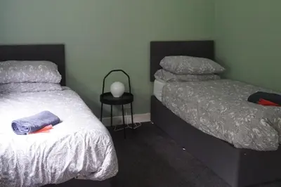 a bedroom with two beds and a table with a lamp at Garnock 1 in Beith