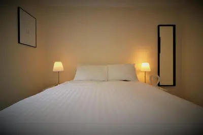 a bedroom with a large white bed with two lamps at Signature - Lincoln View in Knightswood