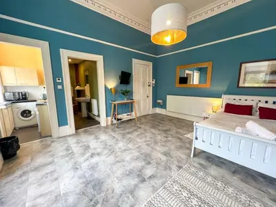 a bedroom with a white bed and a blue wall at Cozy Studio Apartment of Glasgows West End in Glasgow