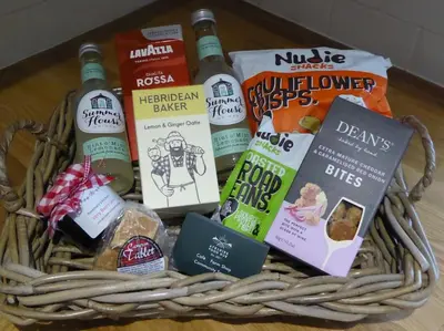 a basket of books and wine bottles on a table at Blackside Cottage - A Luxury Rural Retreat in Mauchline