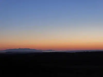 a sunset over a field with mountains in the background at Blackside Cottage - A Luxury Rural Retreat in Mauchline