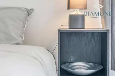 a bed with a night stand with a bowl on it at FOUNDRY - 2 Bedrooms, Fully Equipped, Free Parking, WiFi, FAVOURITE for Contractors, Long Stays Welcome, Food, Bars, Shops by Diamond Short Lets in Dunfermline