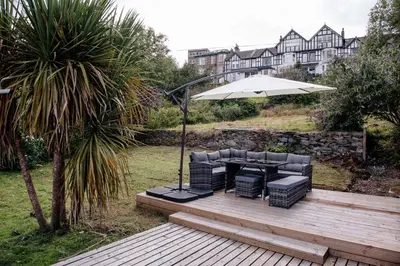 a wooden deck with a table and an umbrella at Otterburn House in Rothesay