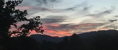 a sunset over a mountain range with a tree at Aquila Retreats in Comrie