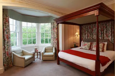 a bedroom with a canopy bed and a chair and window at Best Western Plus Dunfermline Crossford Keavil House Hotel in Dunfermline