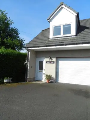 a white house with a garage with a sign on it at Robin's Rest in Auchterarder