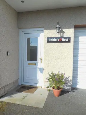 a house with a blue door and a sign on it at Robin's Rest in Auchterarder