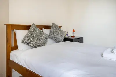 a bedroom with a bed with white sheets and pillows at Bright High-Ceiling 2BD Flat - Central Edinburgh! in Edinburgh