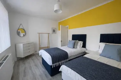 a bedroom with two beds and a yellow wall at Stylish 2-Bed Apartment in Greenock - Sleeps 6 in Greenock
