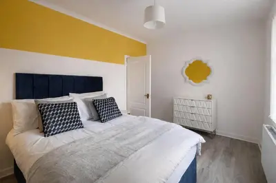 a bedroom with a large bed and a yellow wall at Stylish 2-Bed Apartment in Greenock - Sleeps 6 in Greenock
