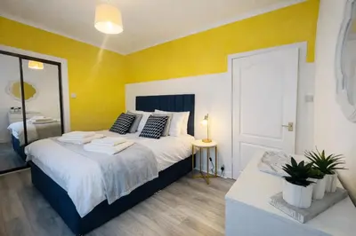 a bedroom with a large bed with yellow walls at Stylish 2-Bed Apartment in Greenock - Sleeps 6 in Greenock