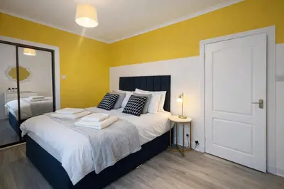 a bedroom with a large bed with yellow walls at Stylish 2-Bed Apartment in Greenock - Sleeps 6 in Greenock