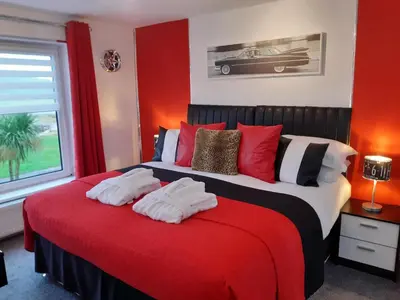 a red bedroom with a bed with towels on it at Cadillac Kustomz Guest House in Rothesay