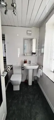 a white bathroom with a sink and a toilet at Cadillac Kustomz Guest House in Rothesay