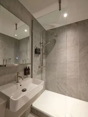 a bathroom with a white sink and a shower at The Resident Edinburgh in Edinburgh