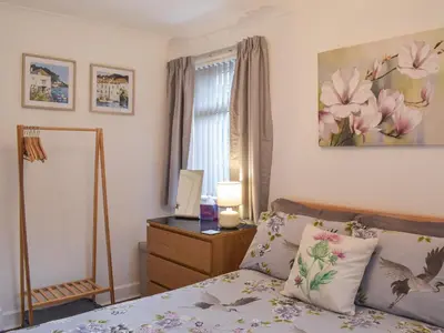 a bedroom with a bed and a desk and a window at Wayside Cottage in Dunoon