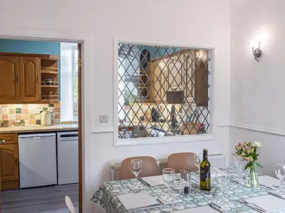 a dining room with a table with a glass window at Wayside Cottage in Dunoon