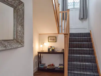 a staircase in a house with a blue patterned carpet at Wayside Cottage in Dunoon
