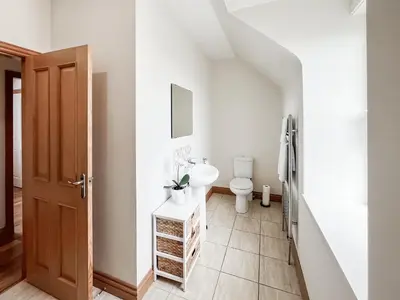 a white bathroom with a toilet and a sink at The Old Cheese Loft in Colfin