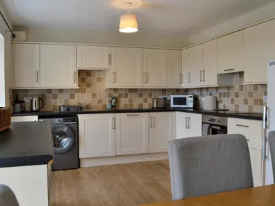 a kitchen with white cabinets and a washer and dryer at The Old Cheese Loft in Colfin