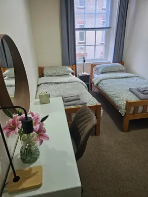 a room with two beds and a table with flowers on it at Ocean View in Campbeltown