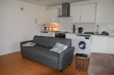 a living room with a couch and a kitchen at The Stable at Drumachro in Isle of Gigha
