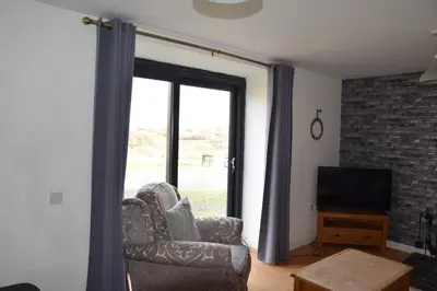 a living room with a chair and a television at The Barn at Drumachro in Isle of Gigha