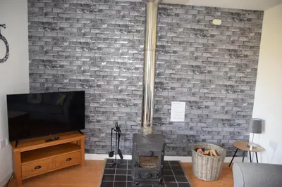 a brick wall with a wood stove in a living room at The Barn at Drumachro in Isle of Gigha