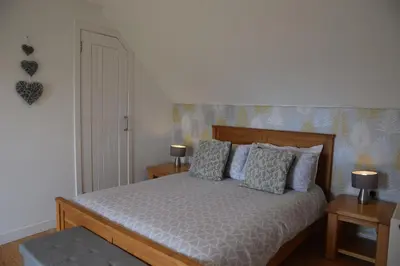 a bedroom with a bed with two tables and two lamps at The Byre at Drumachro in Isle of Gigha