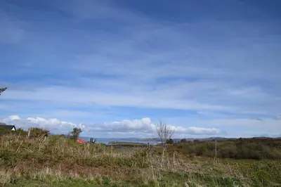 a grassy hill with a blue sky and clouds at The Byre at Drumachro in Isle of Gigha