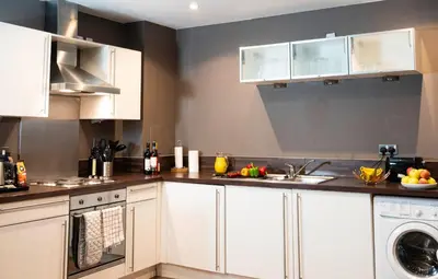a kitchen with white cabinets and a dishwasher at VCity ApartHotels Glasgow Central in Glasgow
