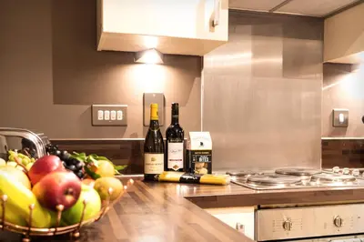 a kitchen with a bowl of fruit and bottles of wine at VCity ApartHotels Glasgow Central in Glasgow