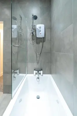 a bathroom with a shower and a bath tub at Bell Apartment in Airdrie