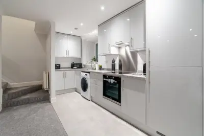 a kitchen with white cabinets and a washer and dryer at Bell Apartment in Airdrie
