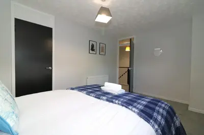 a bedroom with a bed with a blue and white blanket at Signature - Glen Garry House in East Kilbride