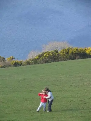 a woman hugging a child in a field at Beautiful spacious old schoolhouse with stunning sea views and beach nearby in Port Bannatyne