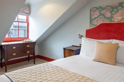 a bedroom with a bed and a dresser and a window at Eleven Stafford Street Townhouse in Edinburgh