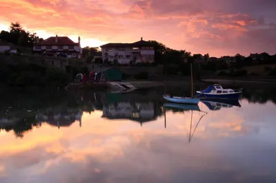 a couple of boats sitting in the water at sunset at Aberdour Hotel, Stables Rooms & Beer Garden in Aberdour