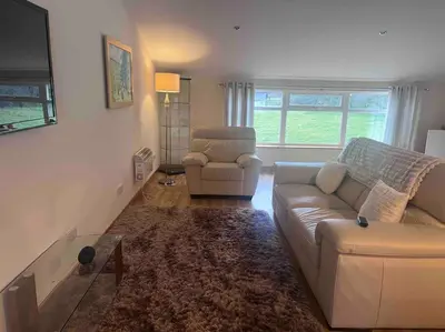 a living room with a couch and a chair at Langside apartments in Newhouse